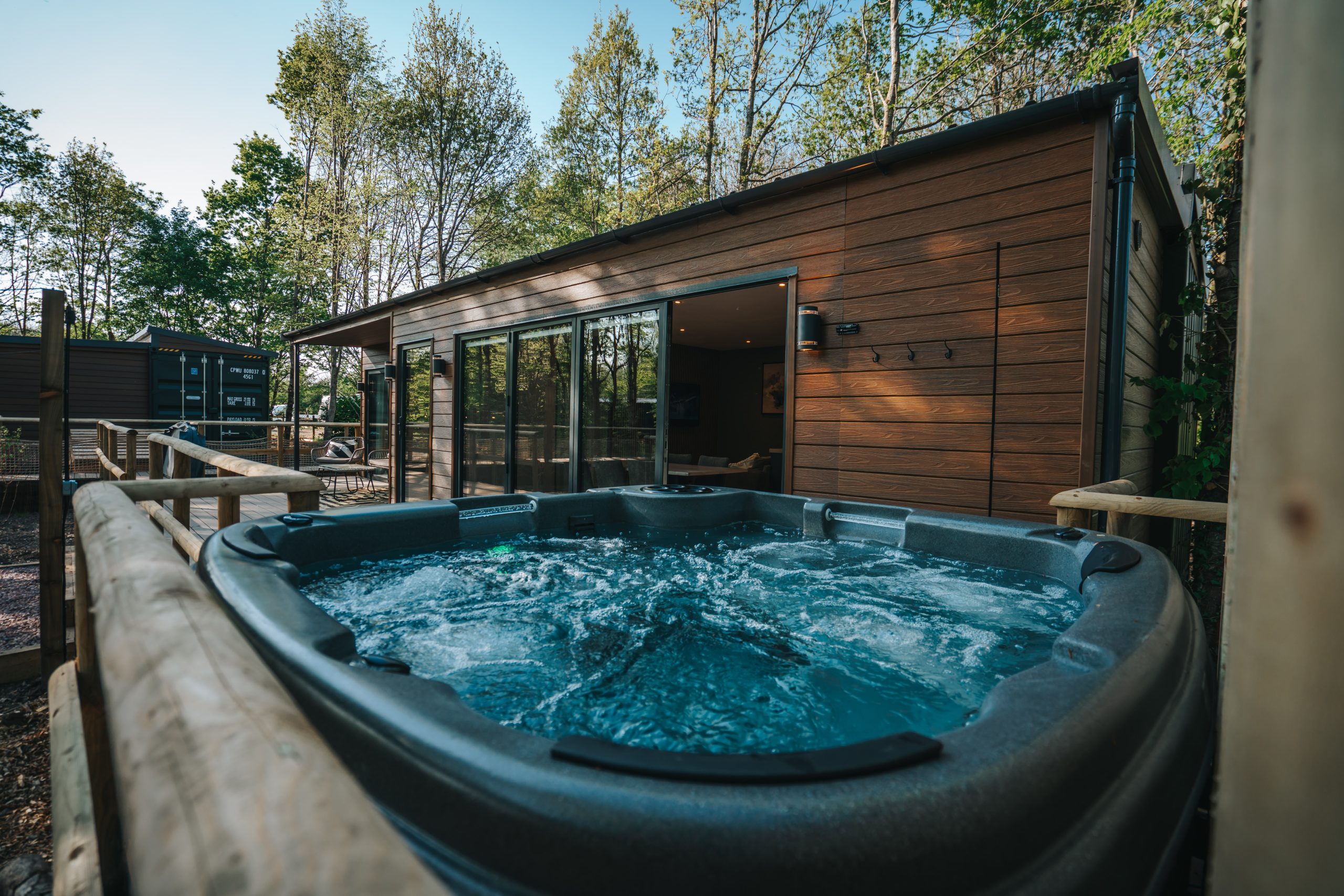 EcoHabs luxury container home with hot tub and forest setting, featuring modern wood exterior, expansive deck, and premium eco-friendly amenities